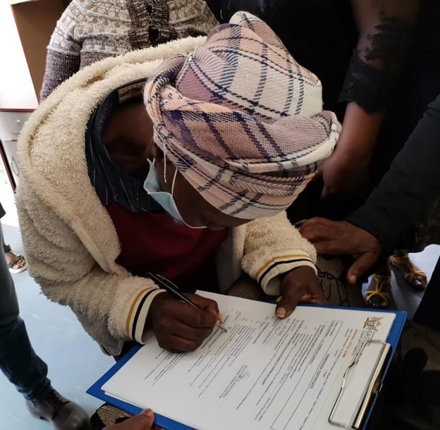 A beneficiary signing off a Happy letter after receiving a brand-new house in Tolofiyeni village.